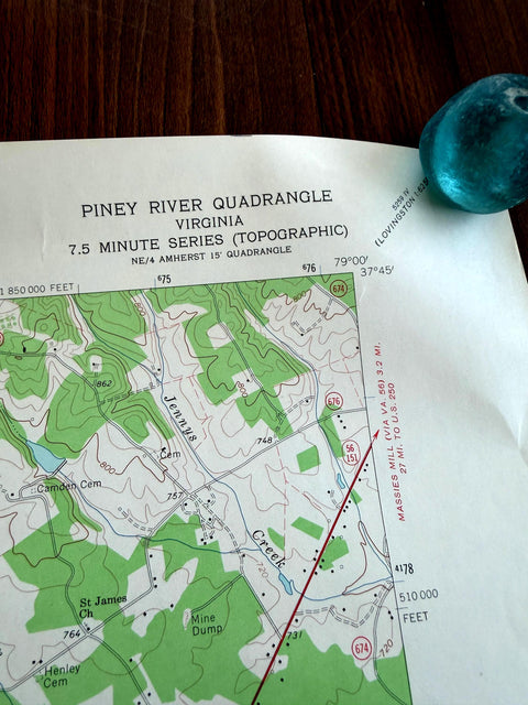 May include: A Piney River Quadrangle topographic map of Virginia featuring green forested areas, contour lines, and text labels for Jennys Creek, St James Ch, and Mine Dump, accompanied by a smooth, translucent teal-colored stone in the corner.